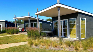 Moderne tiny houses bij Comfort Lodge op Kompas Camping Nieuwpoort in België, tuin en blauwe lucht.