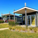 Pequeñas casas modernas en Comfort Lodge, Kompas Camping Nieuwpoort, Bélgica, con césped y cielo azul.