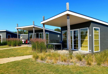 Modern tiny houses at Comfort Lodge, Kompas Camping Nieuwpoort, Belgium, with lawns and sunny blue sky.