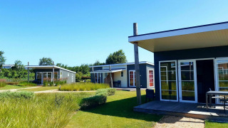 Moderne Tiny Houses am Comfort Lodge, Kompas Camping Nieuwpoort, Belgien, an einem sonnigen Tag mit Garten.