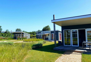 Tiny house moderne al Comfort Lodge, Kompas Camping Nieuwpoort in Belgio, con terrazze e prati verdi.