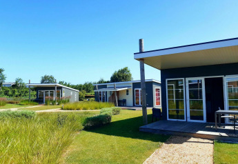 Moderne Tiny Houses am Comfort Lodge, Kompas Camping Nieuwpoort, Belgien, an einem sonnigen Tag mit Garten.