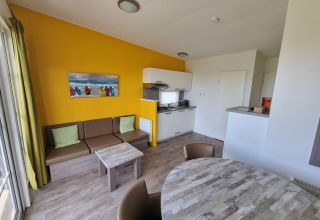 Woonruimte van Comfort Lodge op Kompas Camping Nieuwpoort, België, met moderne keuken, zetel en eettafel.