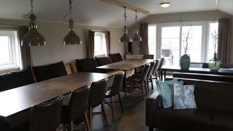Eetruimte met grote tafels en stoelen in de groepslodge bij Holiday park Eigen Wijze, Nederland, helder interieur.
