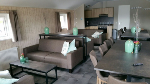 Espace salon intérieur du Group lodge au Holiday park Eigen Wijze, Pays-Bas, avec canapés et tables.