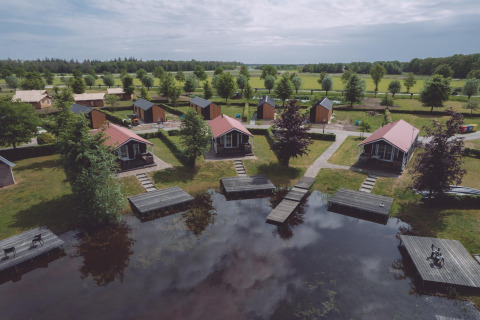 Alojamiento glamping con cabañas junto al lago, vegetación abundante y muelles de madera para relajarse.