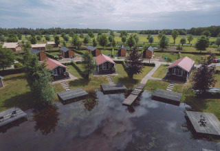 Alojamiento glamping con cabañas junto al lago, vegetación abundante y muelles de madera para relajarse.