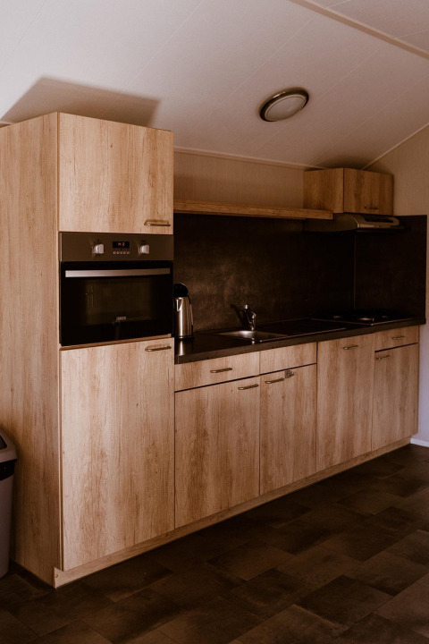 Moderne Küchenzeile mit Holzmöbeln in der Group lodge im Ferienpark Eigen Wijze, Niederlande.
