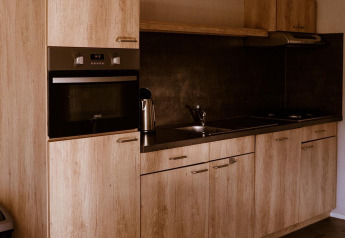 Modern kitchenette with wood finish in the Group lodge at Holiday park Eigen Wijze, Netherlands.