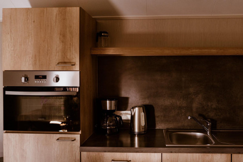 Cocina moderna con horno, cafetera, hervidor eléctrico y fregadero en Group lodge, Holiday park Eigen Wijze, Países Bajos.