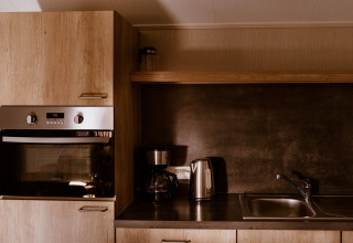Cocina moderna con horno, cafetera, hervidor eléctrico y fregadero en Group lodge, Holiday park Eigen Wijze, Países Bajos.
