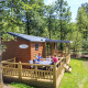 Famiglia si gode un pasto sulla terrazza del cottage a Veluwecamping De Pampel, circondata dalla foresta.