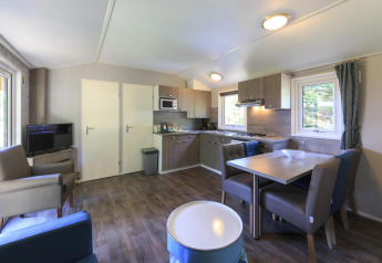 Modern living room and kitchen inside a Cottage at Veluwecamping De Pampel, Netherlands, with dining area.