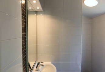 Modern bathroom sink and mirror with white tile walls and ceiling light at Cottage at Veluwecamping De Pampel.