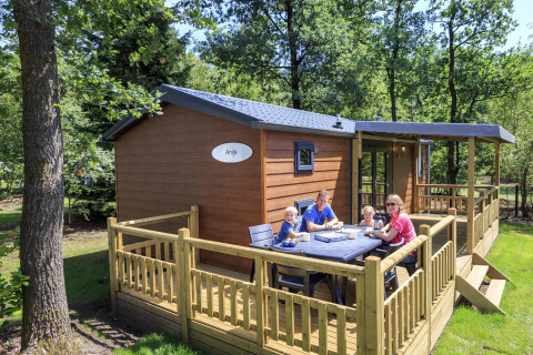 Familia disfruta del desayuno en la terraza de una cabaña en Veluwecamping De Pampel en los Países Bajos.