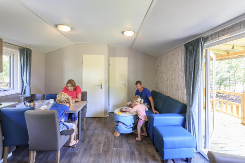 Familia disfrutando junta en una cabaña moderna en Veluwecamping De Pampel, Países Bajos, con niños.