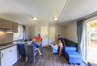 Familia disfrutando en una cabaña en Veluwecamping De Pampel, con cocina y zona de estar.