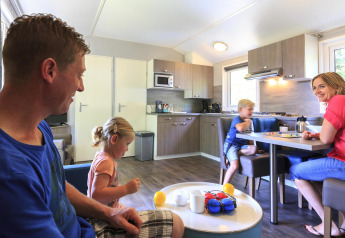 Gezin ontspant in een modern Cottage op Veluwecamping De Pampel in Nederland, met spelletjes en gezelligheid.