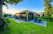 Billede af en moderne Eco Lodge ved Uniq Leisure i Holland, omgivet af grønt græs og træer.