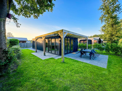 Foto de una moderna Eco Lodge en Uniq Leisure, Países Bajos, rodeada de césped verde y árboles.
