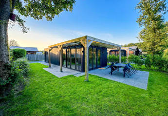Photo of a modern Eco Lodge at Uniq Leisure in the Netherlands, surrounded by green grass and trees.