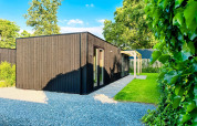 Modern Eco Lodge at Uniq Leisure in the Netherlands, with wooden exterior, garden, and blue sky.