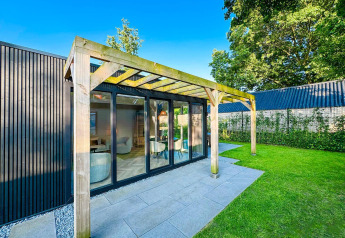 Outdoor view of the Eco Lodge at Uniq Leisure in the Netherlands with modern patio and green lawn.