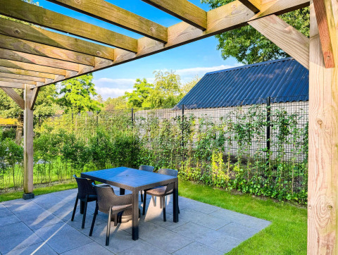 Outdoor patio with pergola and garden furniture at Eco Lodge by Uniq Leisure, surrounded by greenery in the Netherlands.