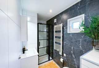 Baño moderno en Eco Lodge en Uniq Leisure, Países Bajos, con detalles de mármol y mampara de vidrio.
