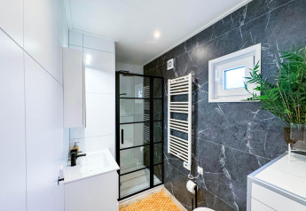 Baño moderno en Eco Lodge en Uniq Leisure, Países Bajos, con detalles de mármol y mampara de vidrio.
