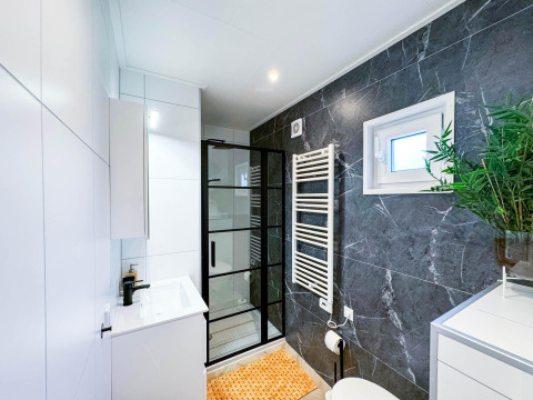 Baño moderno en Eco Lodge en Uniq Leisure, Países Bajos, con detalles de mármol y mampara de vidrio.