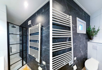 Baño moderno en Eco Lodge en Uniq Leisure, Países Bajos, con pared de mármol negro y ducha elegante.