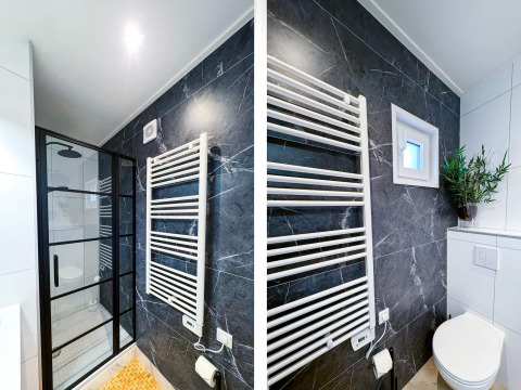 Baño moderno en Eco Lodge en Uniq Leisure, Países Bajos, con pared de mármol negro y ducha elegante.