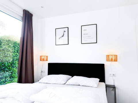 Bright bedroom at Eco Lodge at Uniq Leisure in the Netherlands with double bed, wall art and garden view.