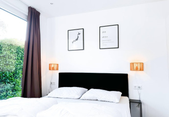 Bright bedroom at Eco Lodge at Uniq Leisure in the Netherlands with double bed, wall art and garden view.