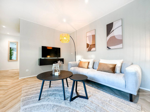 Moderne stue i Eco Lodge på Uniq Leisure, Holland, med lyse farver, sofa, kunst og tv på væggen.