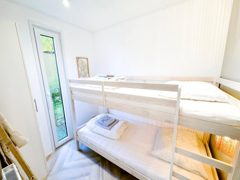 Lyst værelse med køjeseng og udgang til have i Eco Lodge ved Uniq Leisure, Holland.