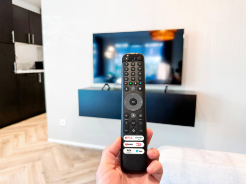 En fjernbetjening peger mod et vægmonteret TV i en moderne stue på Eco Lodge ved Uniq Leisure, Holland.