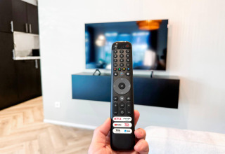 En fjernbetjening peger mod et vægmonteret TV i en moderne stue på Eco Lodge ved Uniq Leisure, Holland.