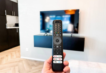 Un control remoto apuntando a un televisor montado en la pared en una sala moderna del Eco Lodge en Uniq Leisure, Países Bajos.