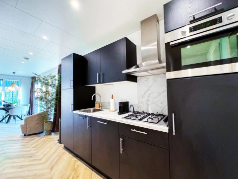 Cocina moderna en Eco Lodge de Uniq Leisure en Países Bajos con muebles oscuros y electrodomésticos empotrados.