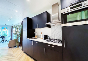 Cocina moderna en Eco Lodge de Uniq Leisure en Países Bajos con muebles oscuros y electrodomésticos empotrados.