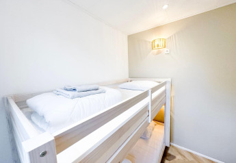 Habitación luminosa con literas en Eco Lodge de Uniq Leisure en los Países Bajos, ropa de cama blanca.