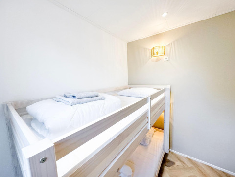 Lyst og moderne køjesengsværelse på Eco Lodge hos Uniq Leisure i Holland, med rene hvide senge.