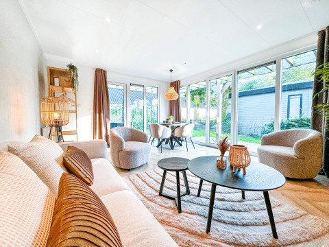 Lys og moderne stue i Eco Lodge ved Uniq Leisure, Nederlandene, med store vinduer og stilfuld indretning.