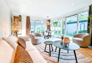 Lys og moderne stue i Eco Lodge ved Uniq Leisure, Nederlandene, med store vinduer og stilfuld indretning.