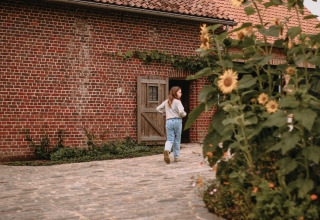 Een meisje wandelt langs de binnenplaats met zonnebloemen bij Feather Down Landgoed ter Wijnendale, West-Vlaanderen.