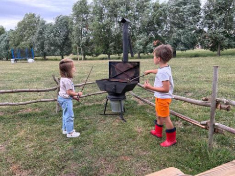 Twee kinderen spelen bij een buitenfornuis in het park van Feather Down Landgoed ter Wijnendale, West-Vlaanderen.