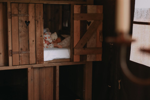 Niño duerme con peluches en una cabaña de madera acogedora en Feather Down Landgoed ter Wijnendale.
