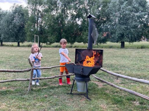 Dos niños asan malvaviscos sobre el fuego en Feather Down Landgoed ter Wijnendale, parque vacacional de Bélgica.